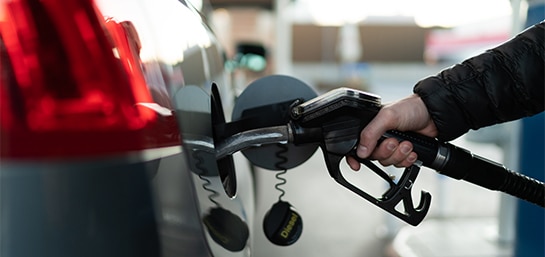 Auto en estacion de servicio con surtidor de combustible